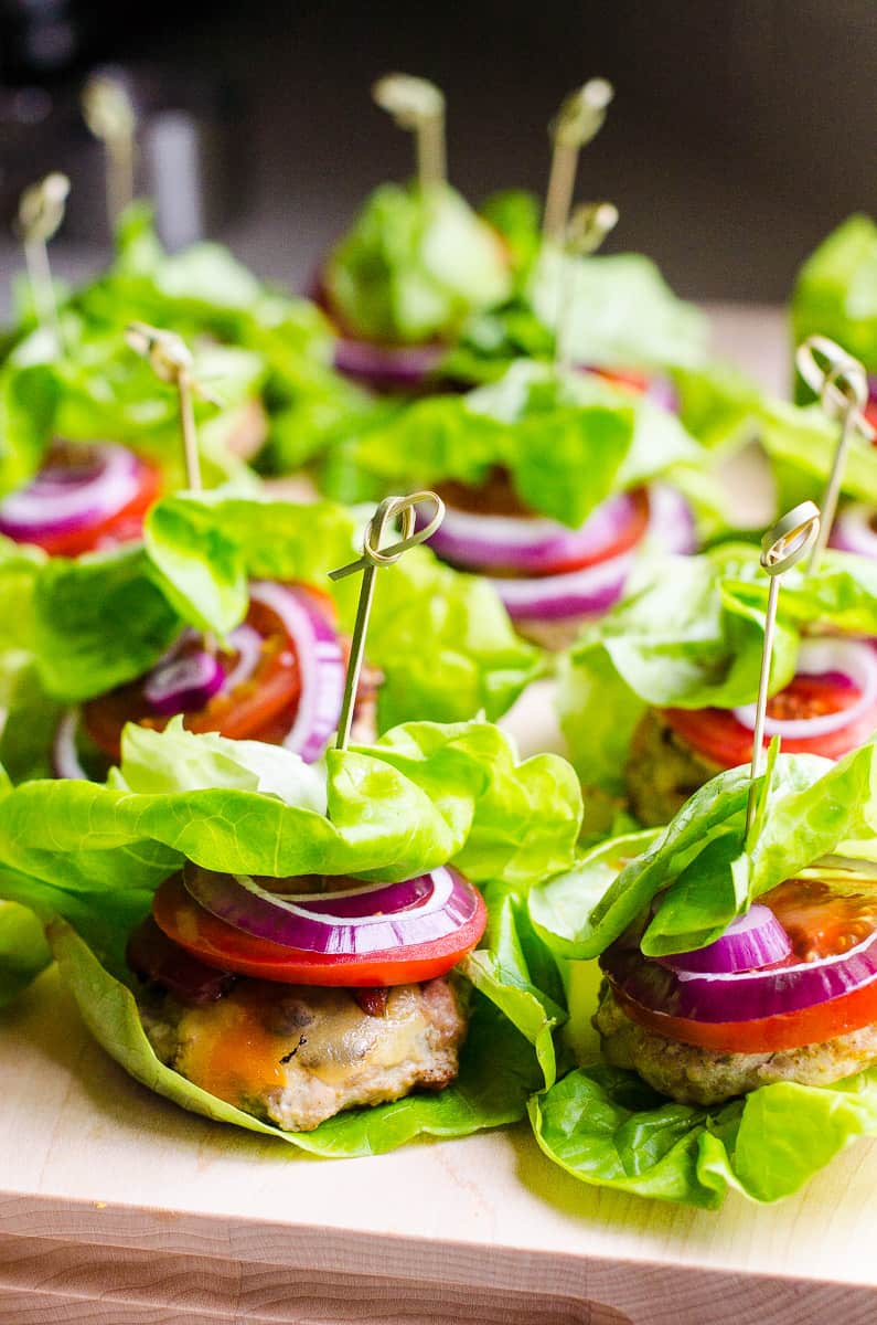 turkey sliders wrapped in lettuce leaves with sticks and served on a board