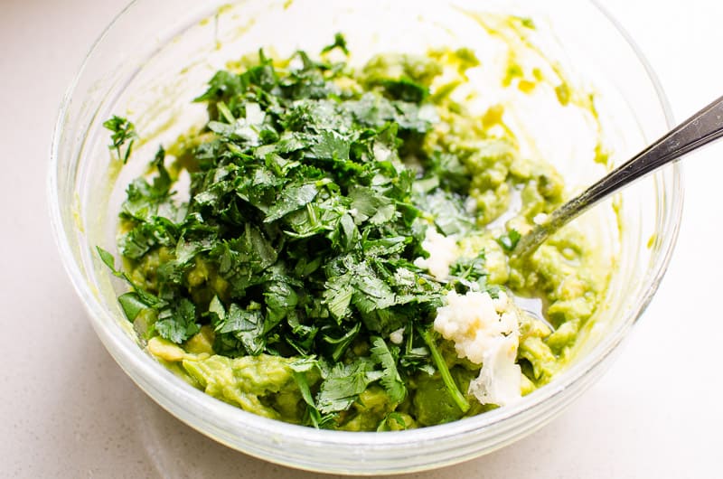 Frozen avocado mashed in a bowl with cilantro and garlic.