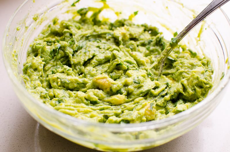 Mashed frozen avocado guacamole in bowl. 