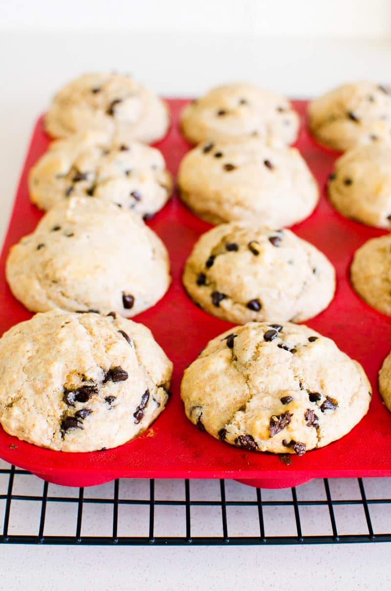 Healthy chocolate chip muffins in red silicone muffin tin on top of wire rack.