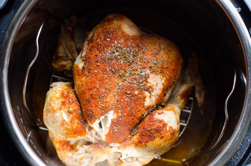 Cooked Instant Pot whole frozen chicken in pressure cooker pot on a trivet.