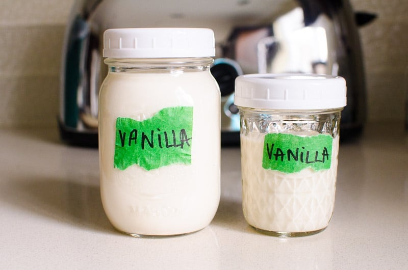 2 glass jars with white lids and vanilla yogurt inside