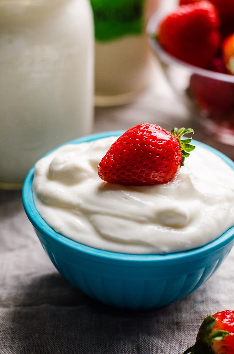 Instant Pot yogurt served in a blue bowl and garnished with strawberry.