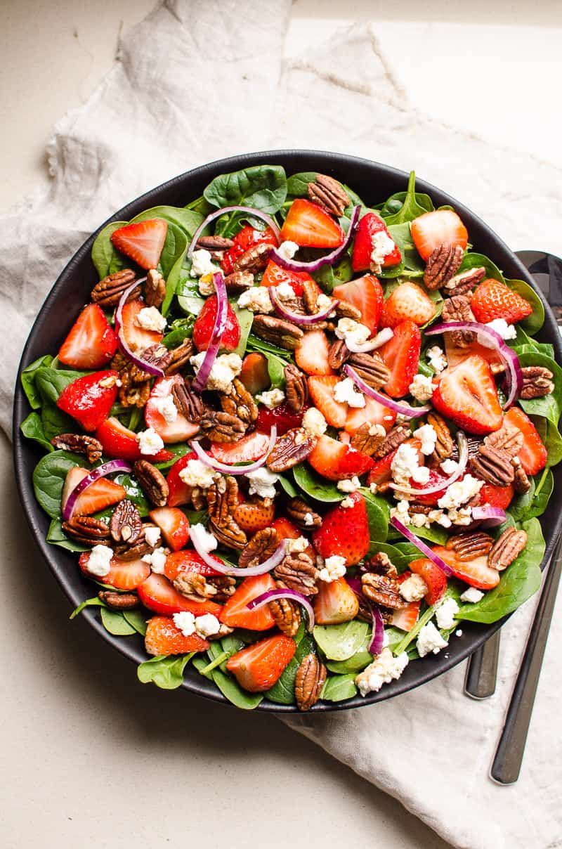Strawberry and spinach salad with pecans in a serving bowl. 