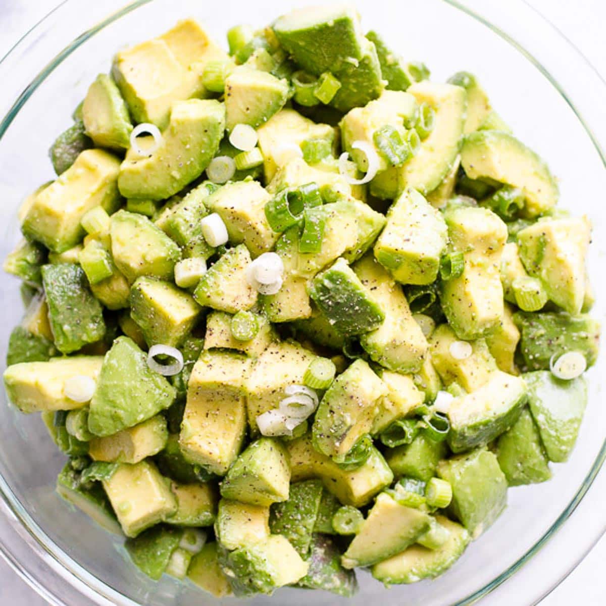 Simple avocado salad in a bowl with green onions.