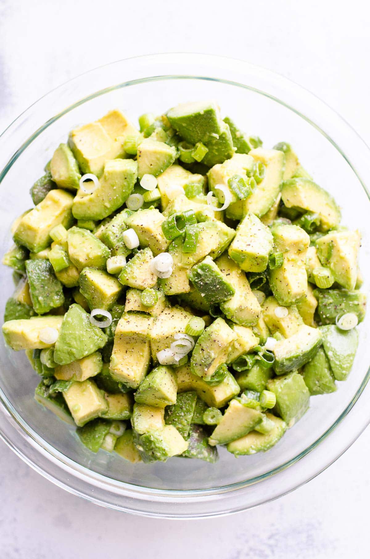 Simple avocado salad with green onions and black pepper in a bowl. 