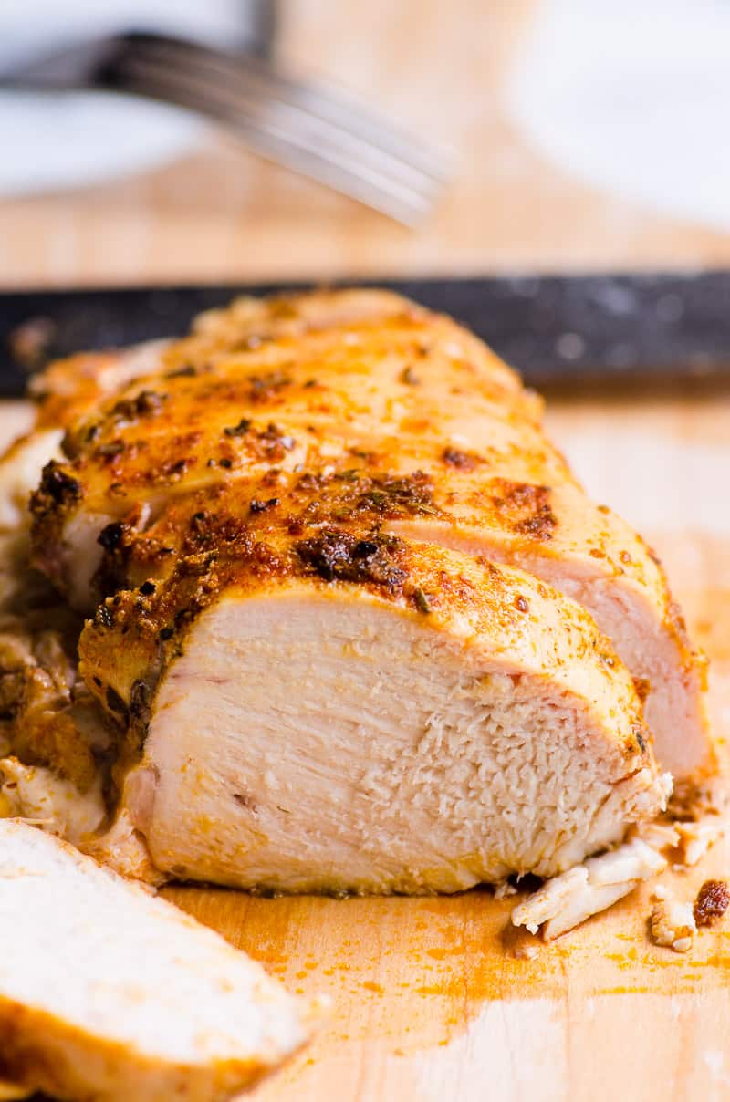 Sliced baked chicken breast on cutting board showing texture.