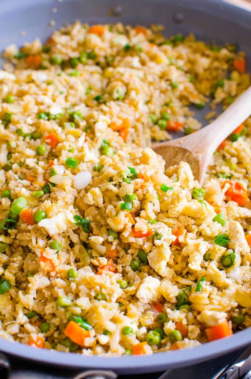 Cauliflower fried rice with peas and carrots in skillet.