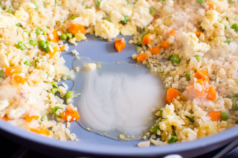Honey added to cauliflower fried rice in a skillet.