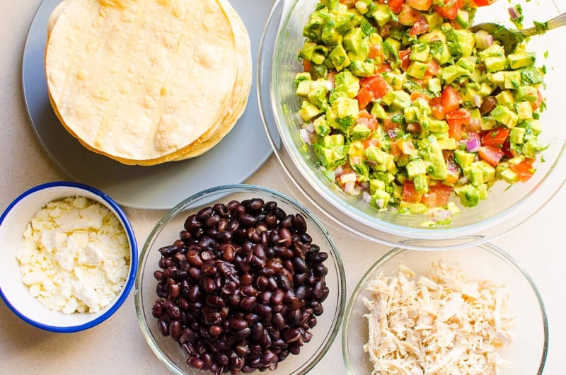 black beans, shredded chicken, salsa, cheese and tostada shells in bowls and plates
