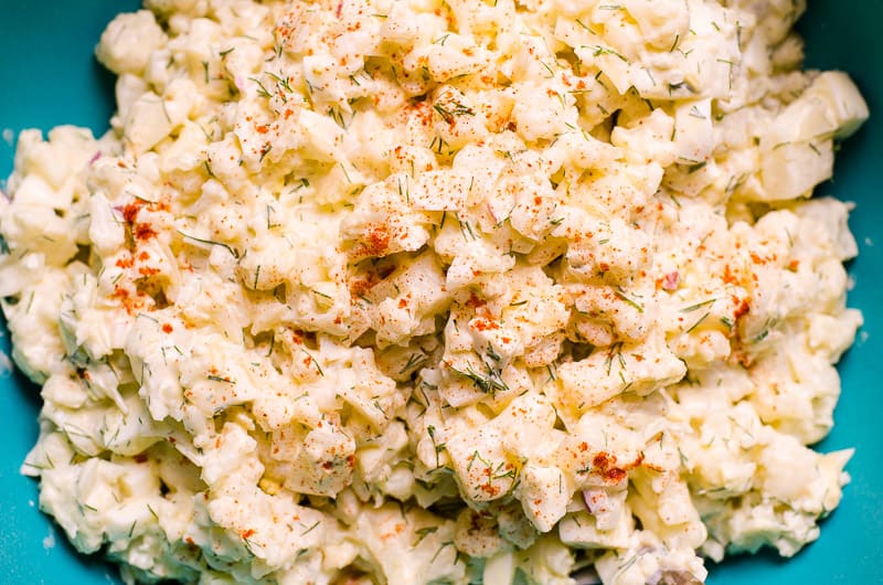 Healthy cauliflower potato salad sprinkled with paprika in blue bowl.