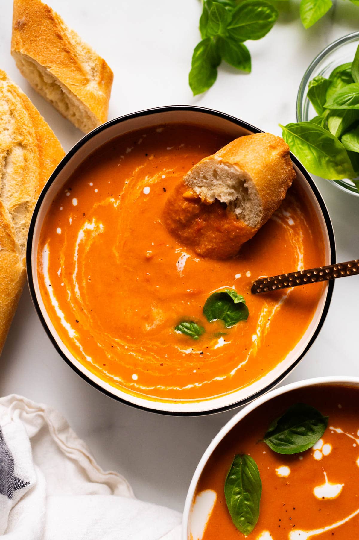 A bowl with creamy tomato soup and bread dipped in it.