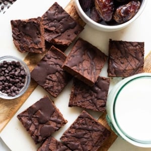 No bake brownies on a serving board. Milk in a glass, dates and chocolate chips in bowls.