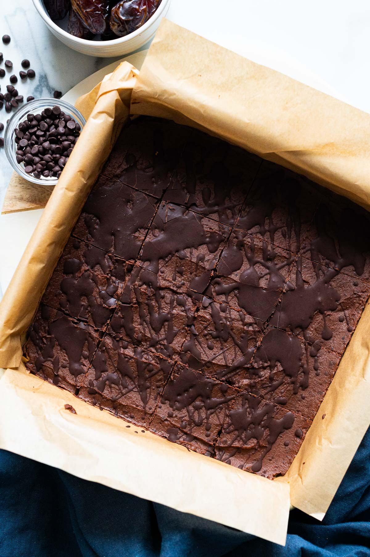 A pan with sliced brownies drizzled with chocolate.