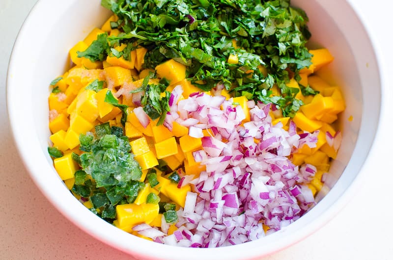 Chopped mango, cilantro, red onion, jalapeno in a bowl.