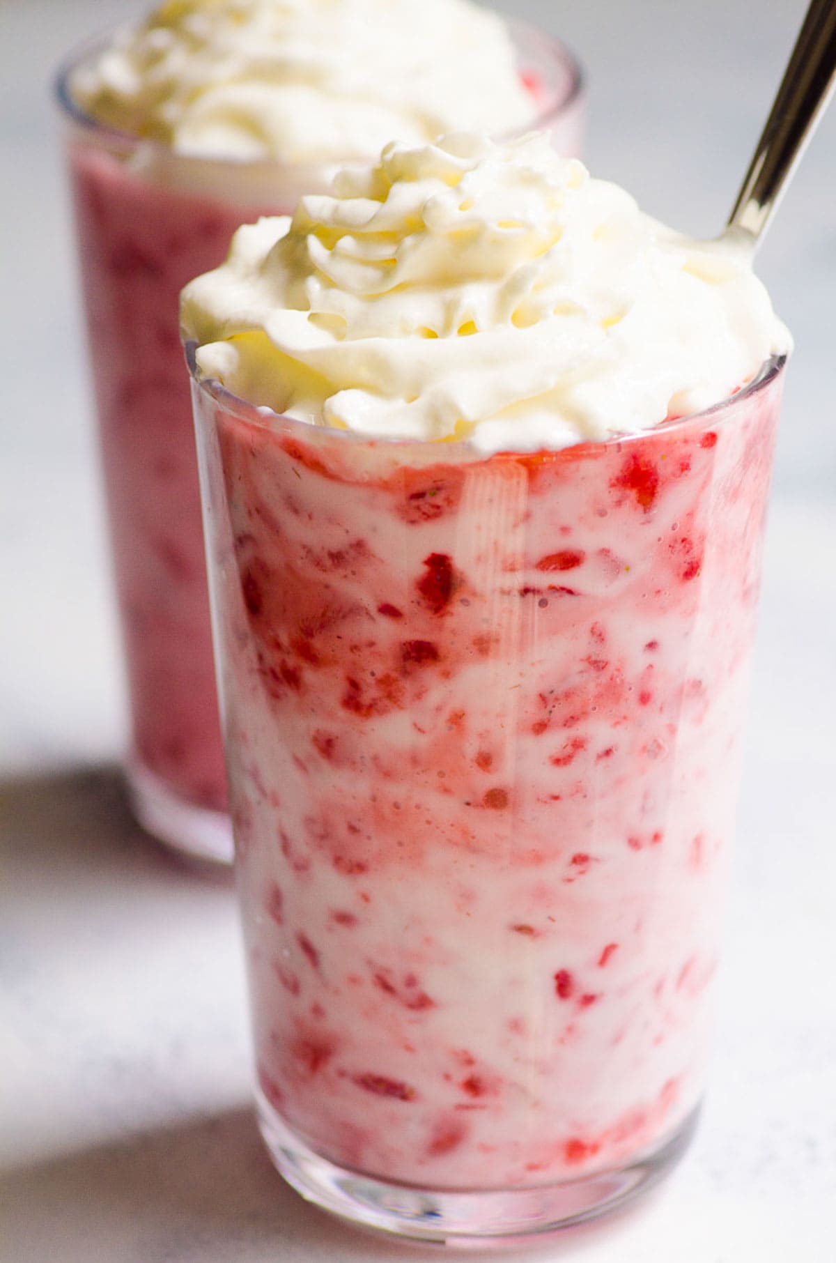 Strawberry yogurt topped with whipped cream in a glass.