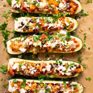 Mediterranean zucchini boats garnished with parsley on a baking sheet.