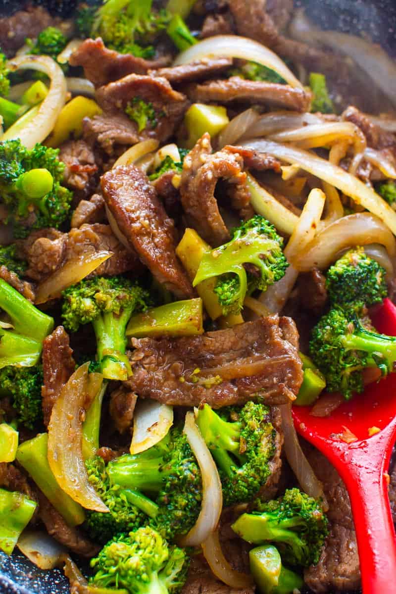 Healthy Beef and Broccoli in black skillet with red spoon.