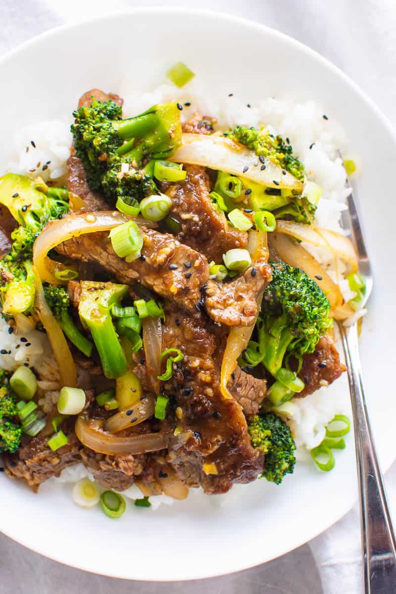 Healthy Beef and Broccoli stir fry recipe in a bowl with rice and black sesame seeds garnish