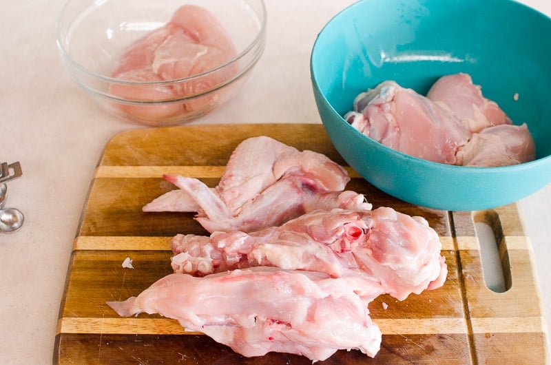 Cut up chicken on a cutting board and in bowls.