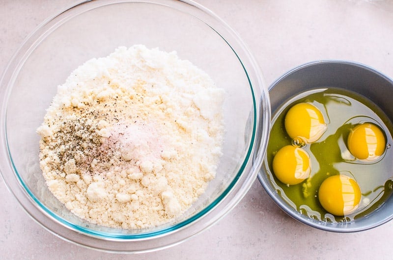 bowl of flour, coconut flakes and seasoning, and a bowl of eggs