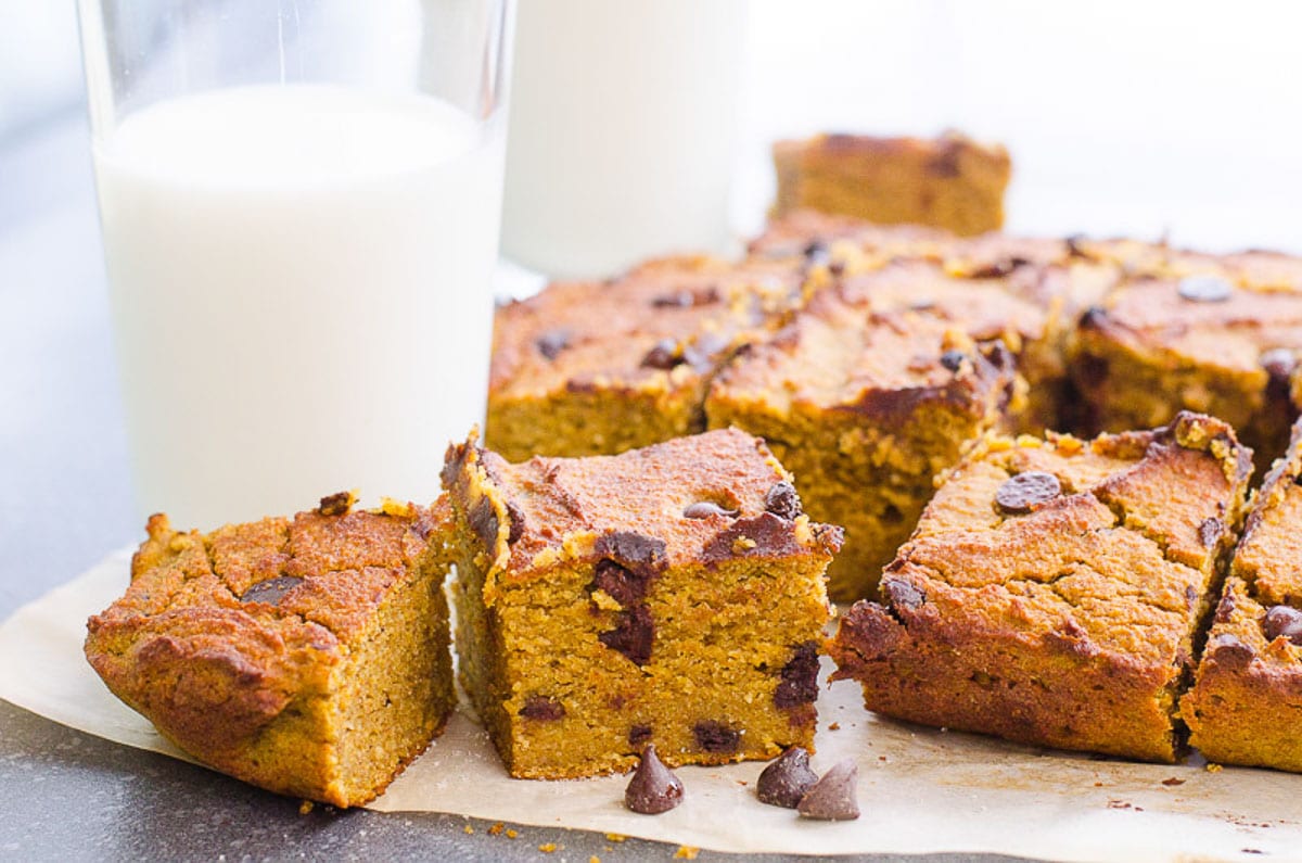 pumpkin bars on parchment paper served with a tall glass of milk