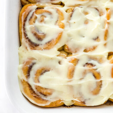 Healthy cinnamon rolls with cream cheese frosting in bakign dish.