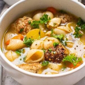 Turkey meatball soup garnished with parsley in white pot.