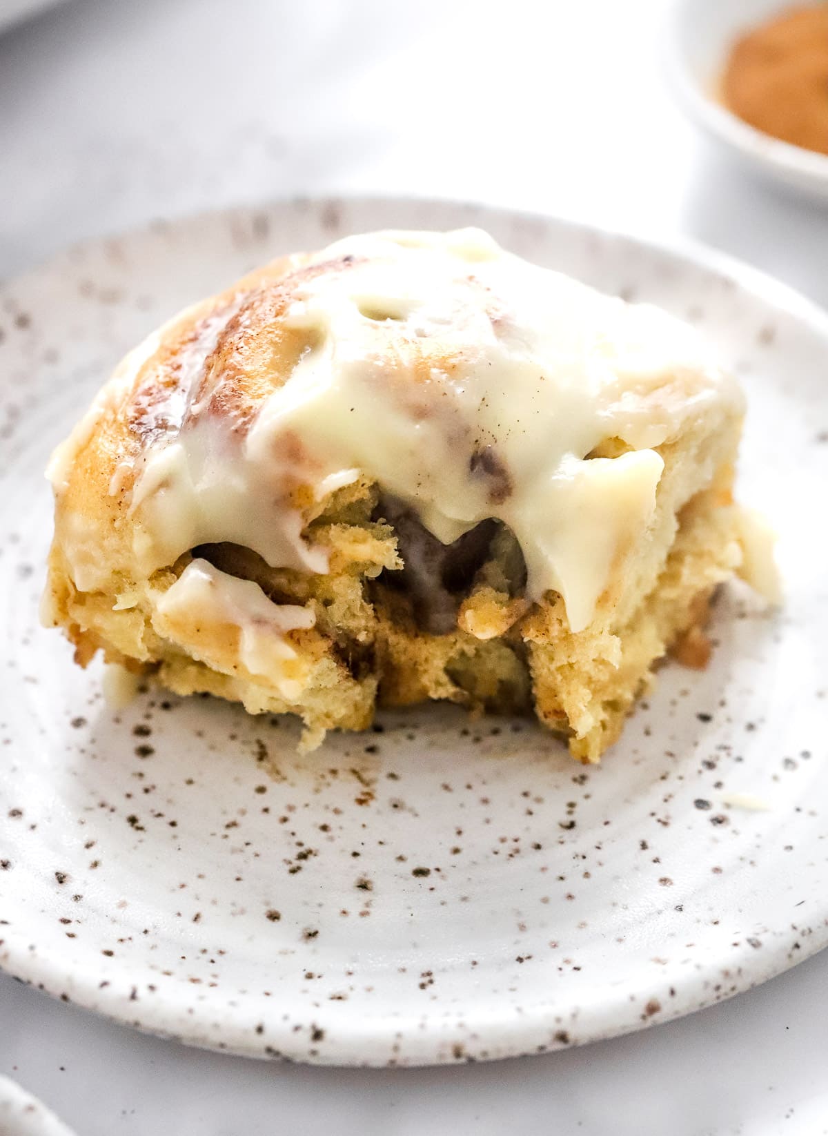 Whole wheat cinnamon roll with bite taken out on a plate.