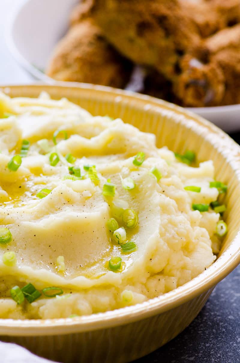 Healthier mashed potatoes garnished with green onion in a pie dish.