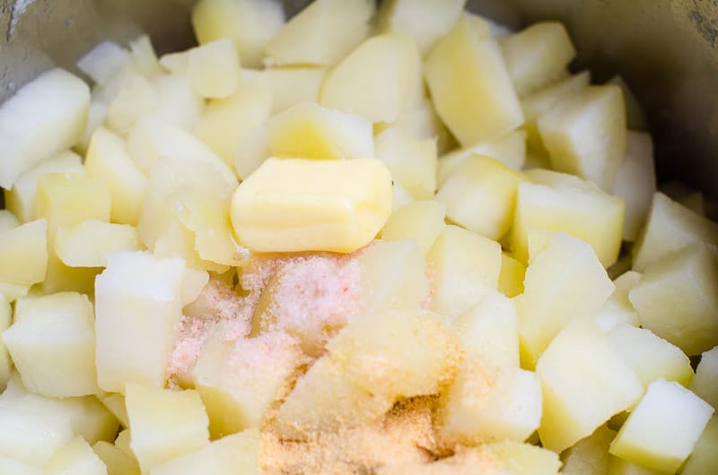 Butter and salt added to a pot with drained cooked potatoes.