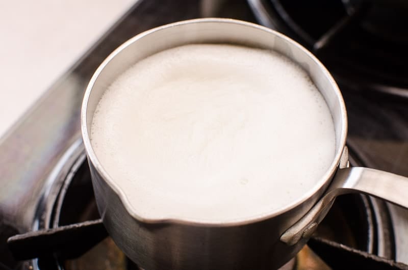 Saucepan with hot milk on a stove.