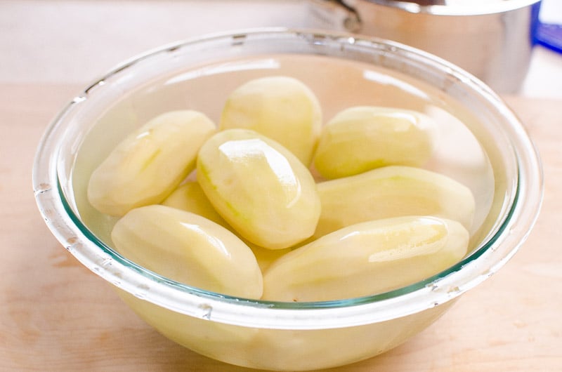 Peeled potatoes in a bowl with cold water.