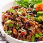 Instant Pot rice and beans garnished with cilantro and green onion and served on white plate.