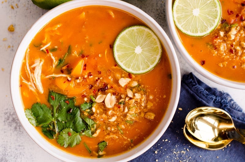 bowl of instant pot thai chicken soup garnished with peanuts, lime slice and cilantro