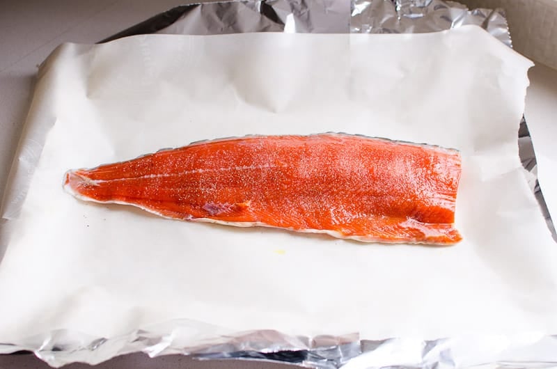 salmon fillet laying on top of parchment paper and foil