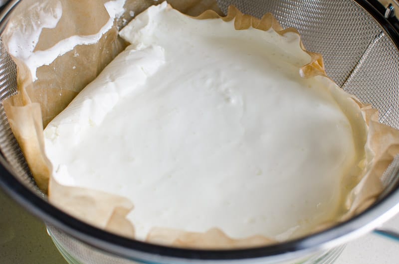 Yogurt draining in a colander lined with coffee filters.