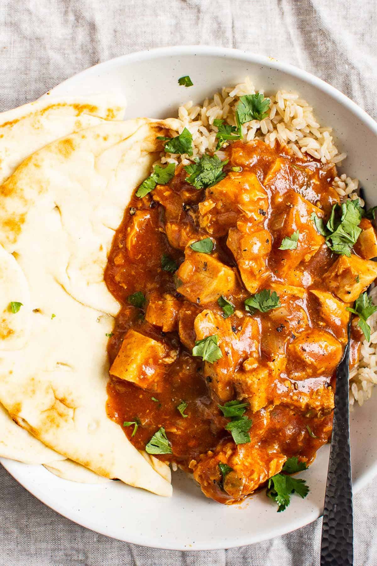 Instant pot butter chicken served with  naan, rice and garnished with cilantro.