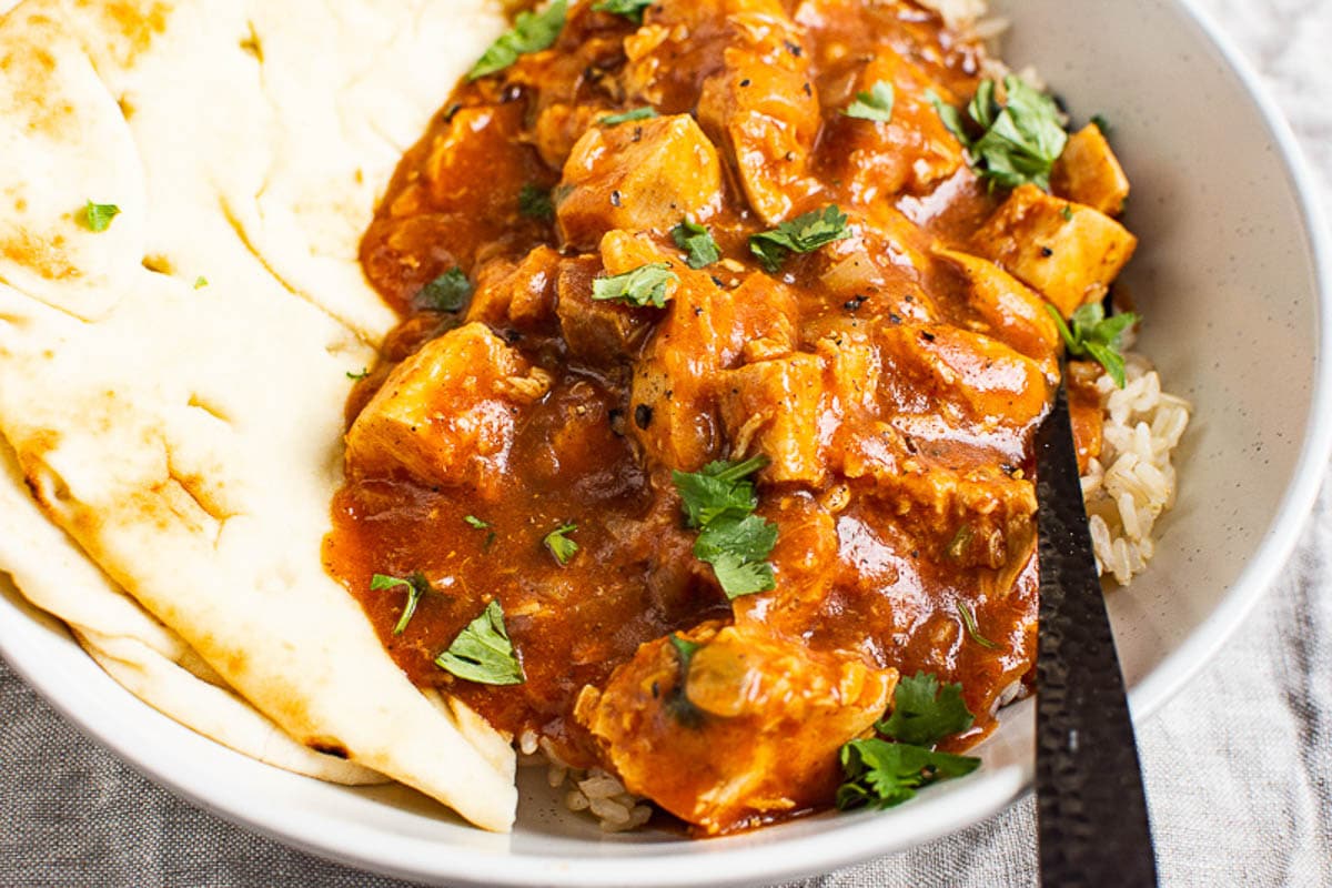 bowl of instant pot butter chicken served over rice with naan bread