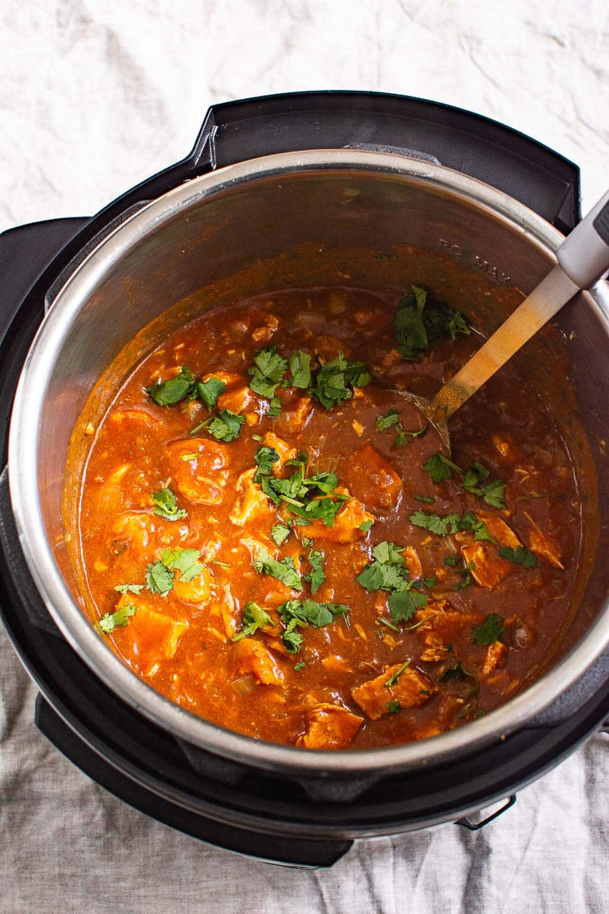 Instant pot butter chicken in pressure cooker pot with metal spoon.