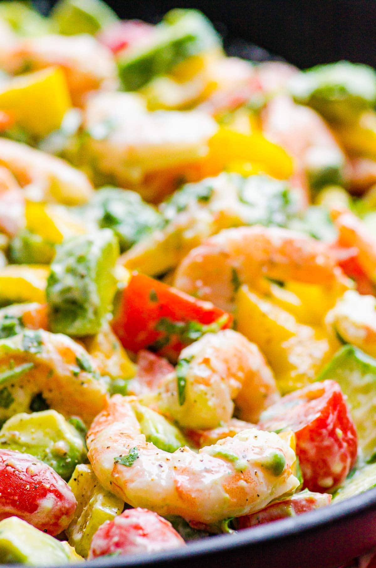 Closeup of shrimp avocado salad with tomatoes, peppers and creamy yogurt dressing.