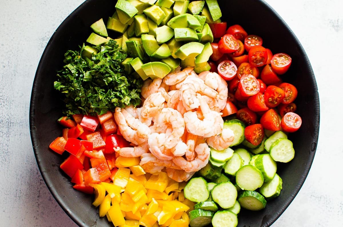 Shrimp and veggies in black bowl.
