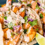 Shrimp tacos with slaw and lime served on a plate.