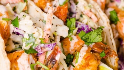 Shrimp tacos with slaw and lime served on a plate.