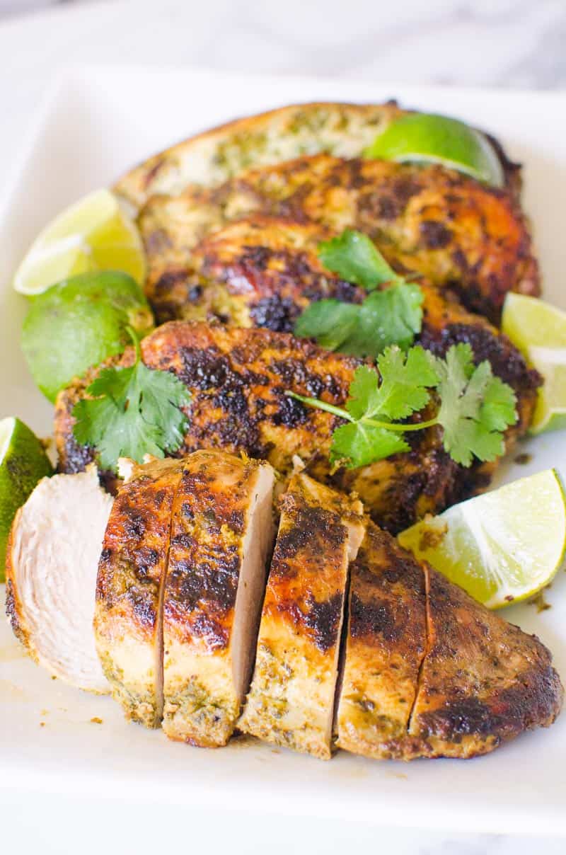 Sliced cilantro lime chicken breasts garnished with cilantro and limes.