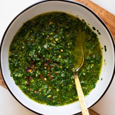 Chimichurri recipe in white bowl with a spoon.