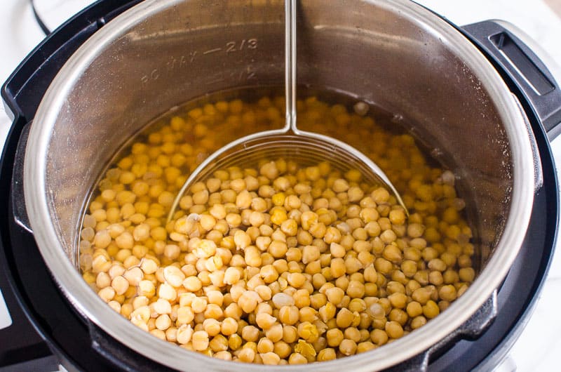 Cooked garbanzo beans in the pot with a strainer. 