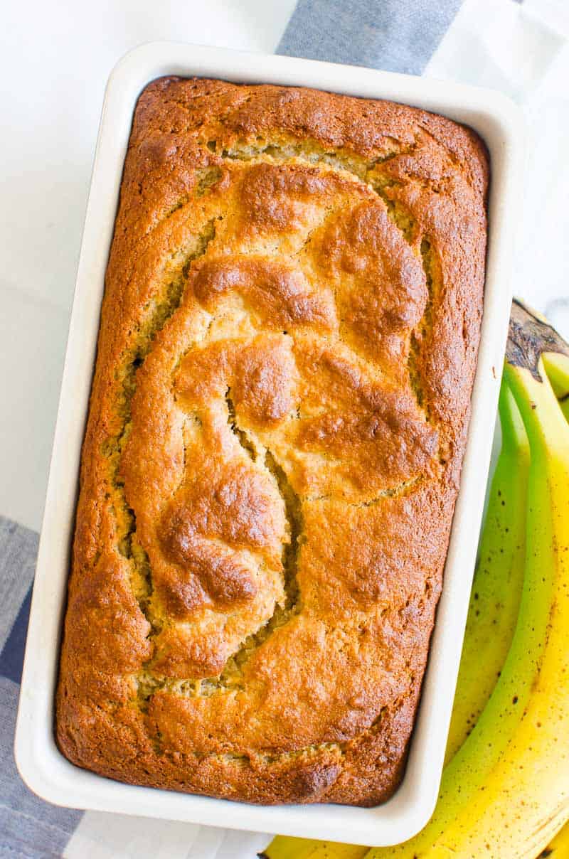 almond flour banana bread in a loaf pan with bananas on a side