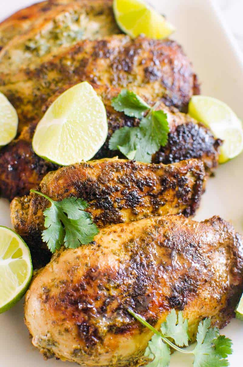 Cilantro lime chicken on a platter garnished with lime and cilantro.