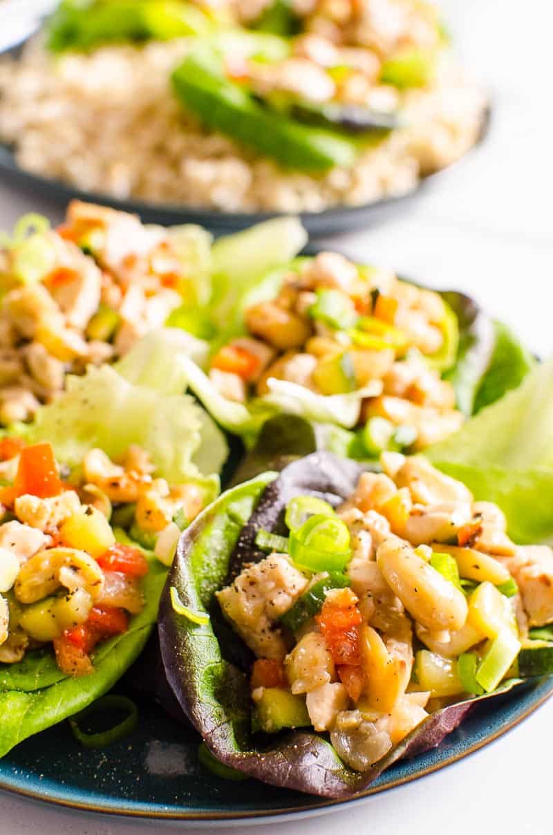 Healthy chicken lettuce wraps with cashews and green onions served on a plate.